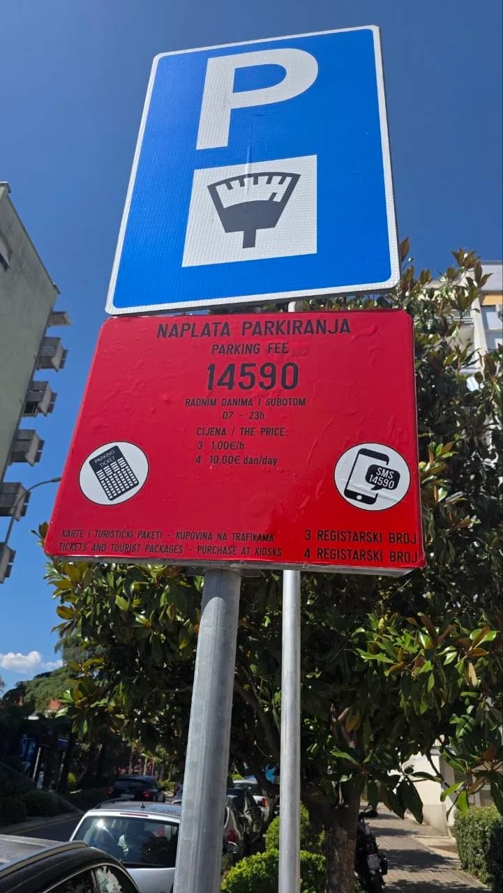 Crvena tabla sa oznakom zone 14590, radnim vremenom naplate i cijenom po satu i danu, ispod plavog znaka za naplatu parkiranja